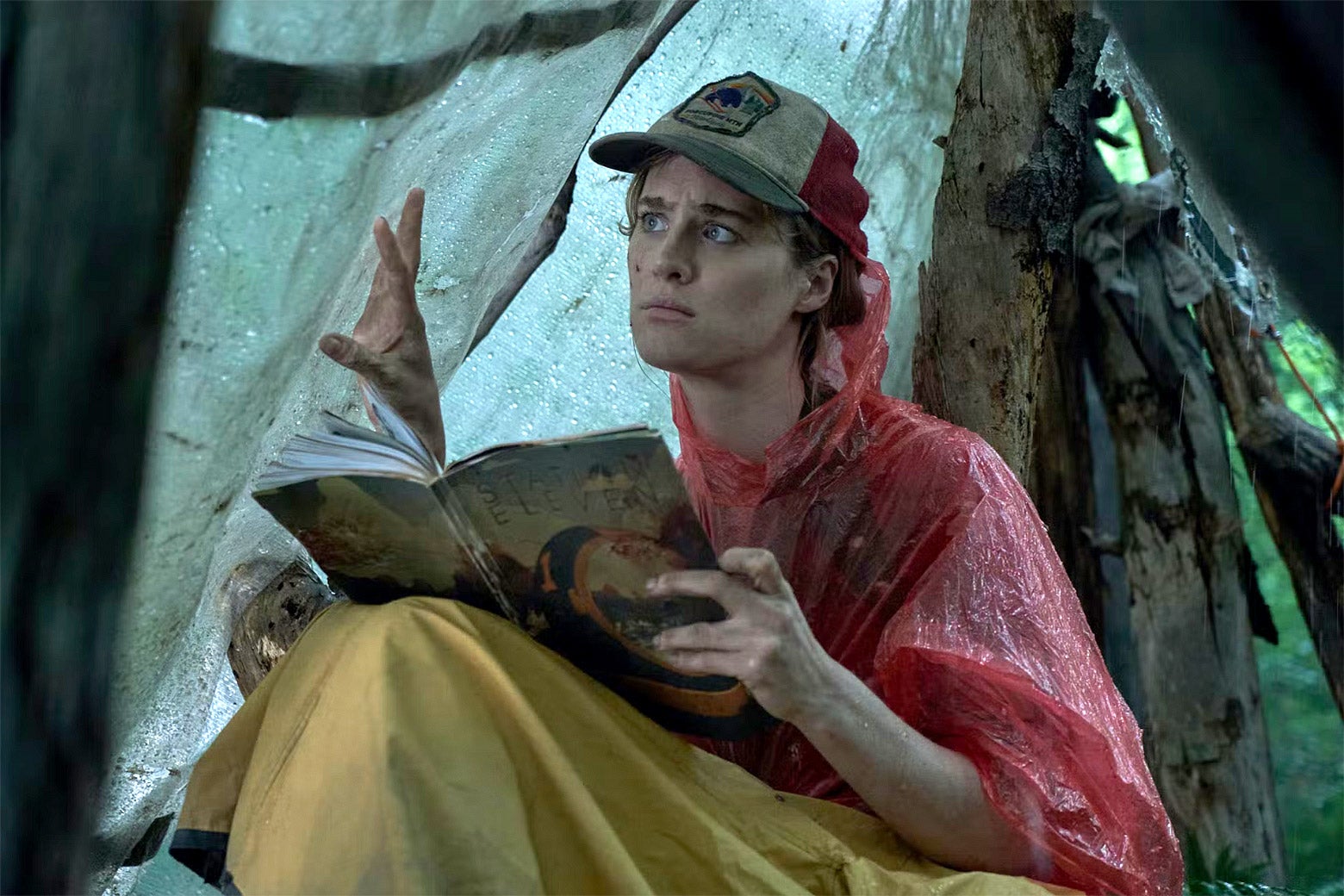Mackenzie Davis sitting in a tent outdoors and reading a book in a scene in Station Eleven.