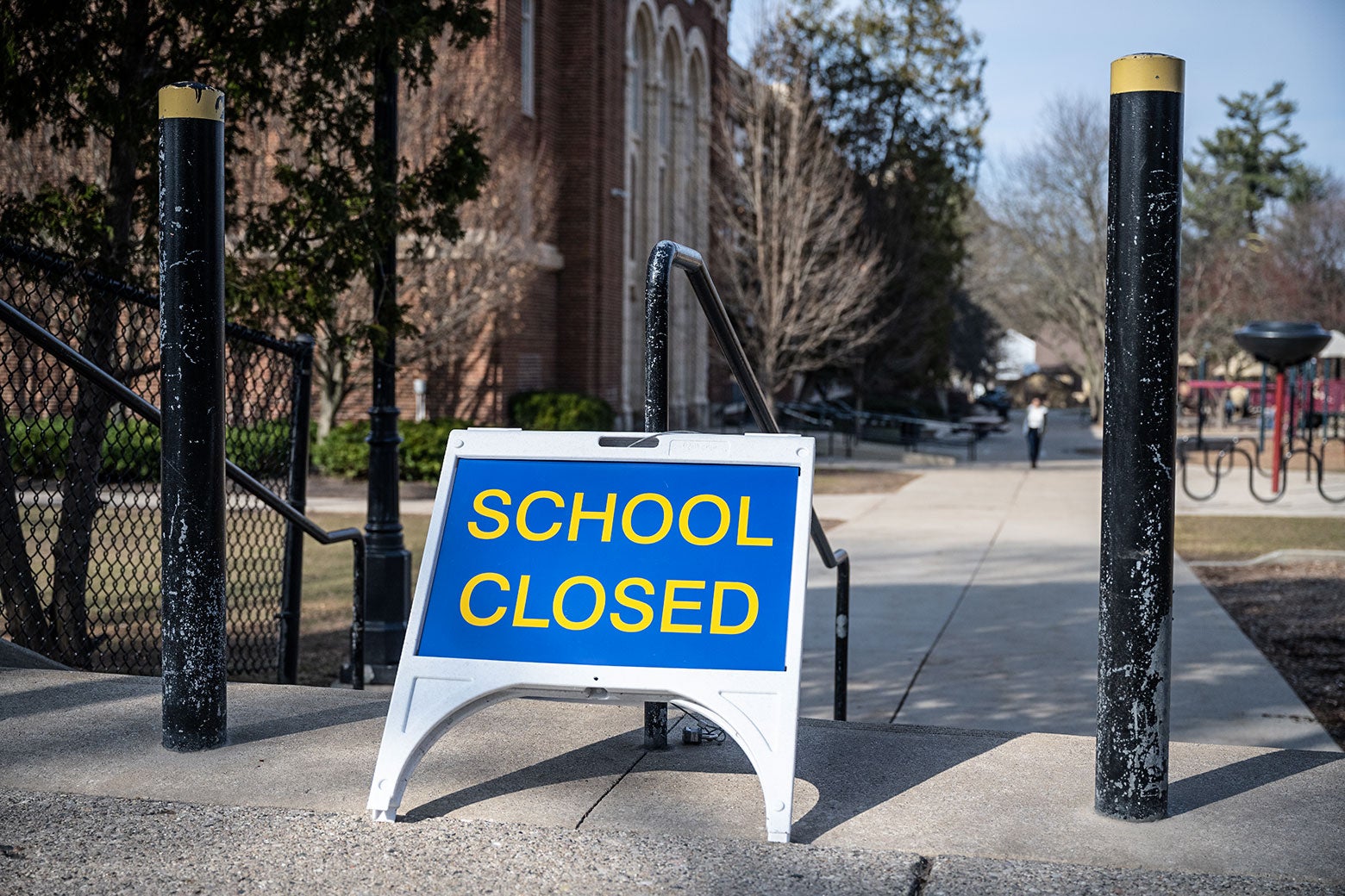 A sign that says, "School closed" outside of a brick building.