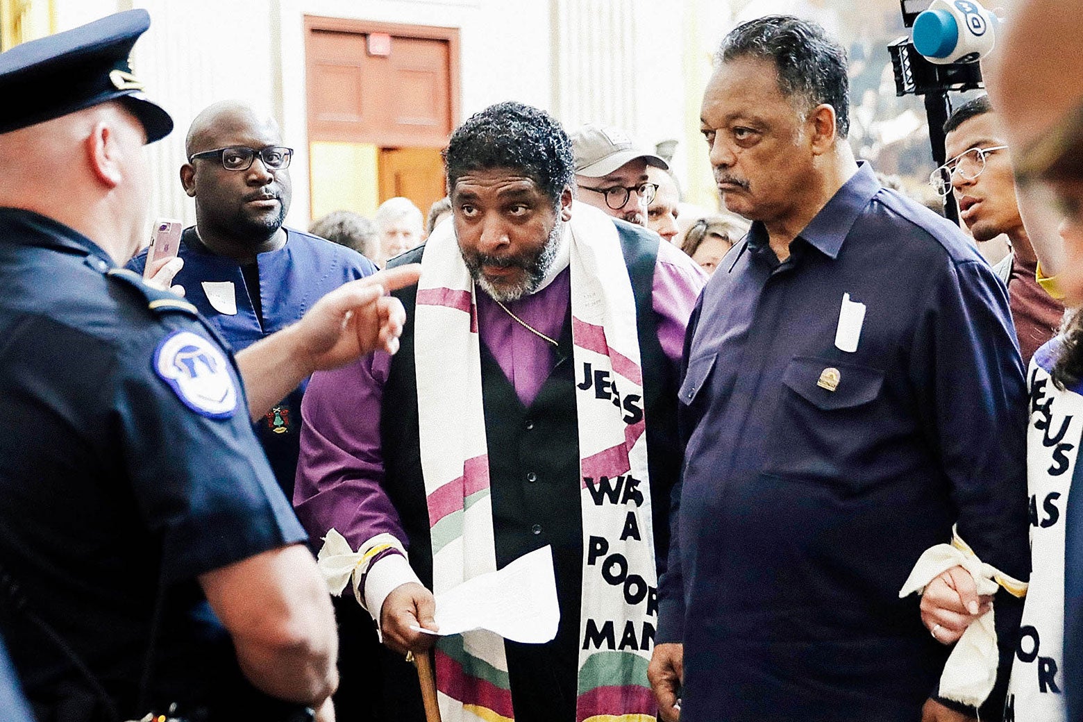 Police stop the Rev. William Barber, the Rev. Jesse Jackson, and other clergy and demonstrators attempting to deliver a letter to the Senate on May 21 at the U.S. Capitol in Washington. Barber is wearing a scarf with the words "Jesus Was a Poor Man" visible.