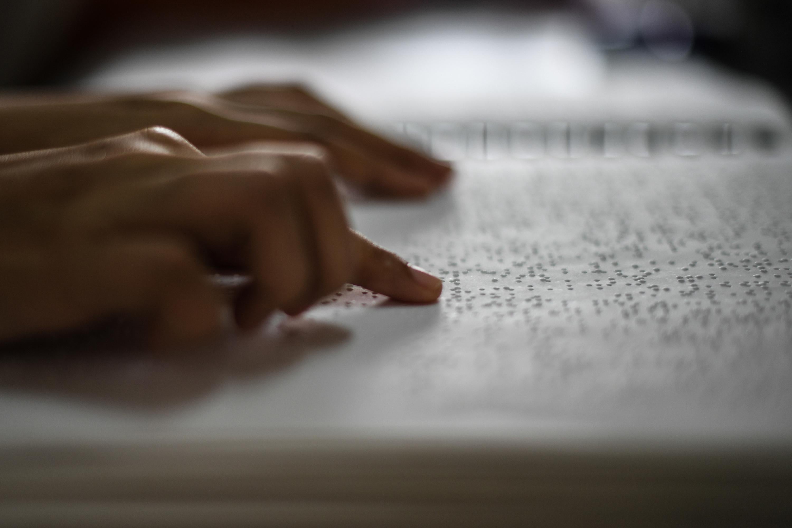 A visually impaired person reads a page in Braille.