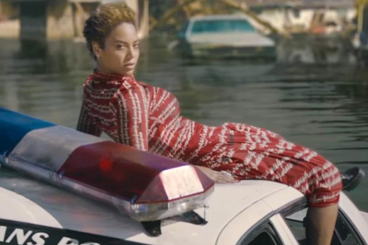 In a still from the "Formation" video, Beyoncé reclines on a police car floating in floodwaters.