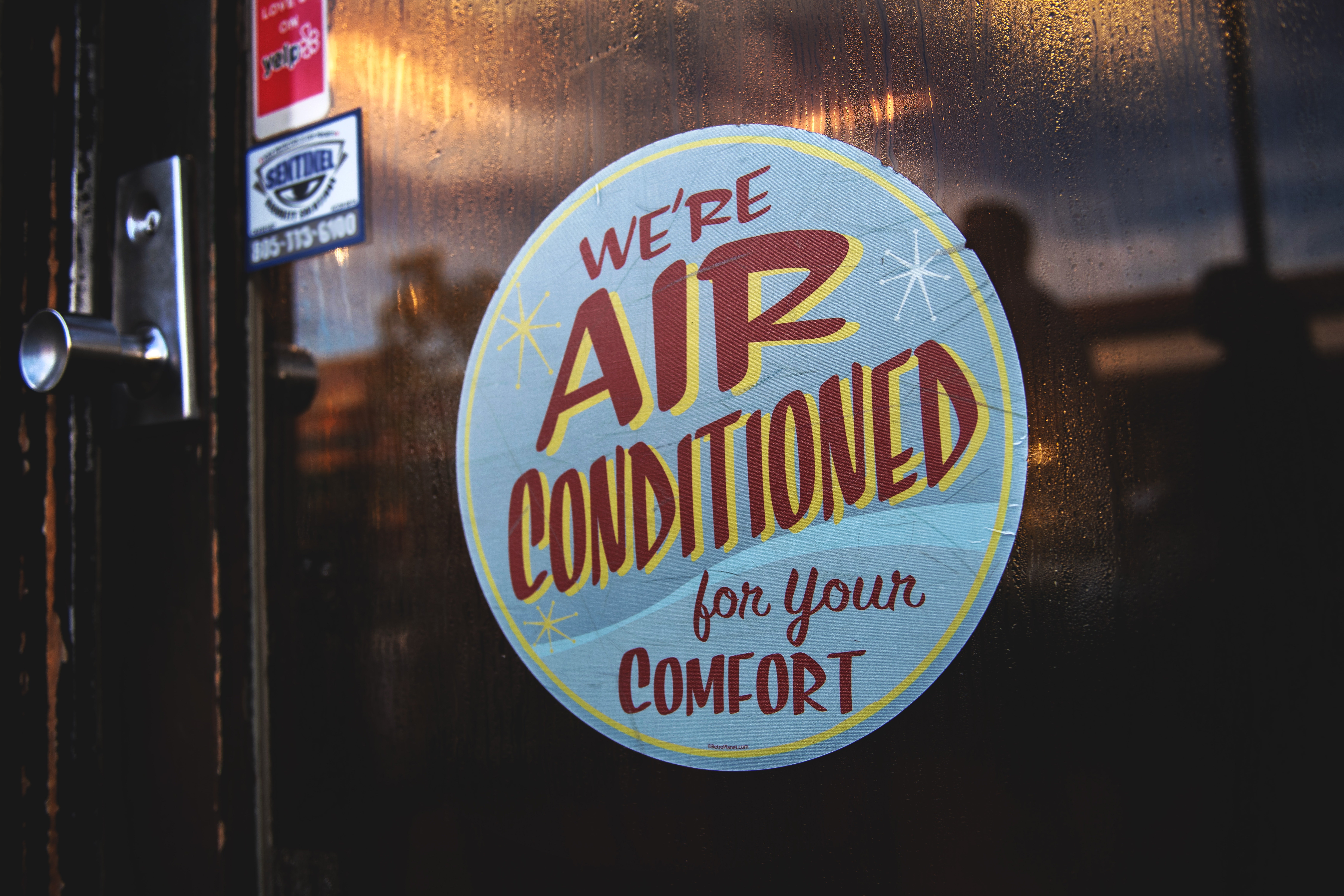 A sign on a door says "We're air conditioned for your comfort."