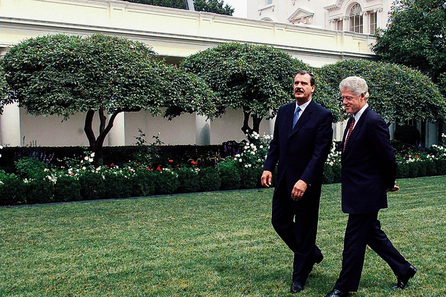 Bill Clinton walks with Vicente Fox through the White House Rose Garden.