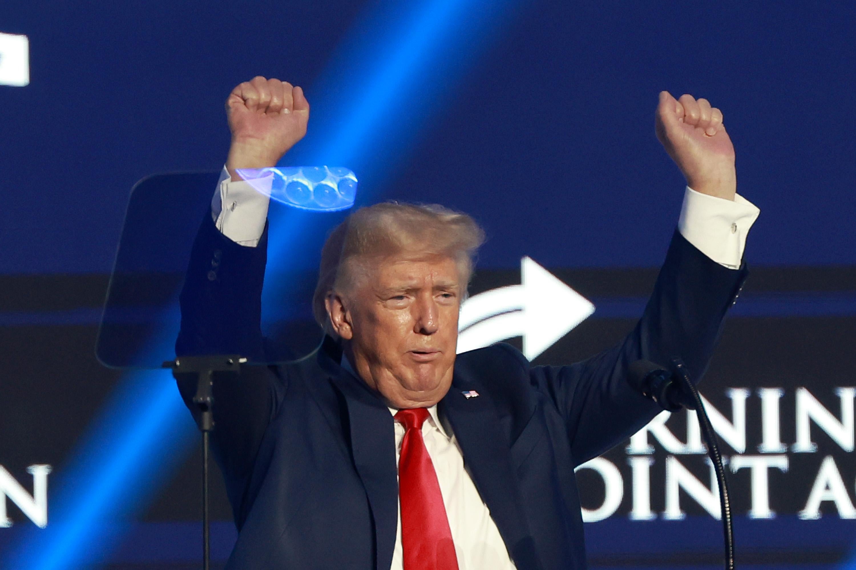 Trump sticks his hands in his air near a teleprompter, looks worried.