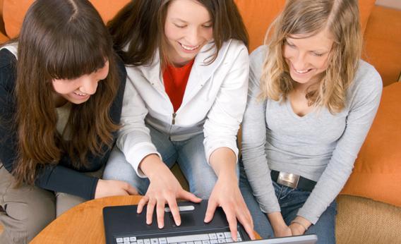 Three young women around a computer.