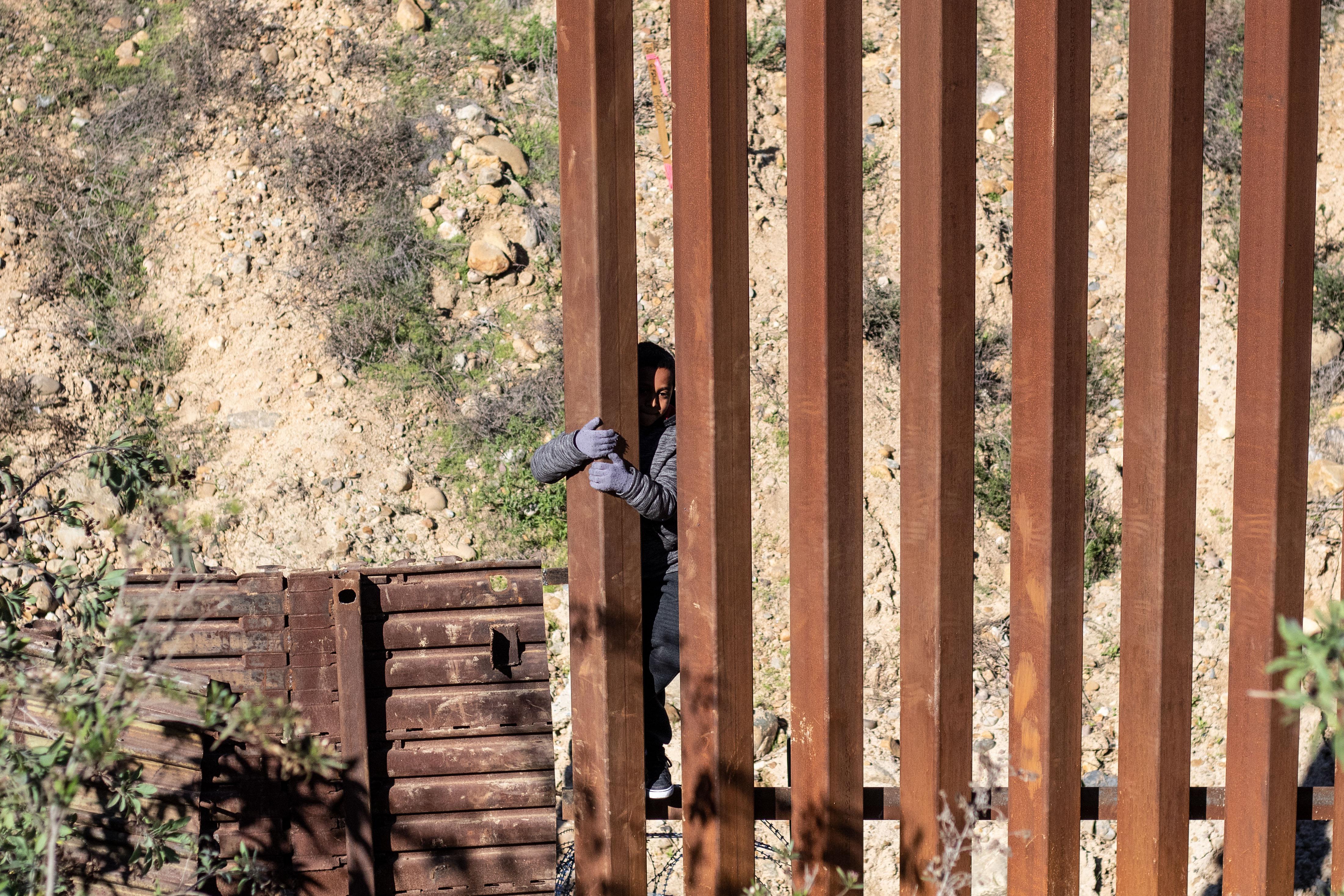 Mexican migrant child Kevin Andres, from Guerrero state, crosses the US-Mexico border fence from Tijuana to San Diego County in the US, as seen from Tijuana, Baja California state, Mexico, on December 28, 2018. 