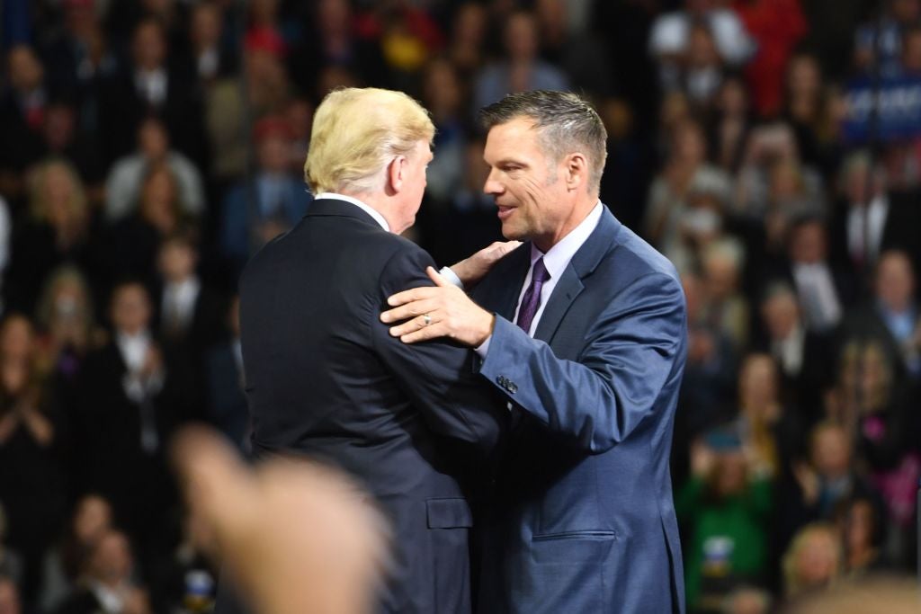 Trump and Kobach with their hands on each other's shoulders, onstage at a rally.