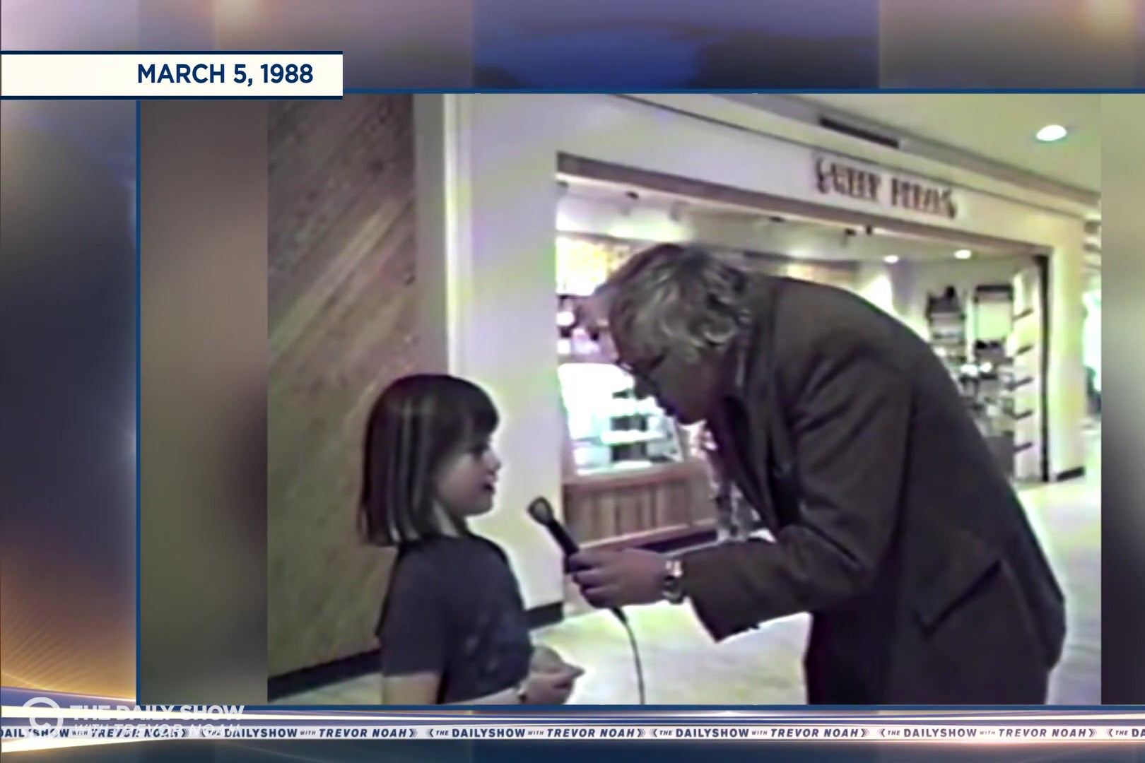A still from Bernie Sanders' public access show in which he is leaning way over to interview a very short little girl.