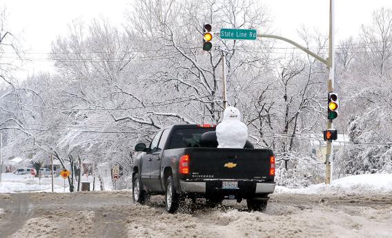 A pickup truck with a snowman in the back drives through the snow on Feb. 26 in Kansas City, Missouri.