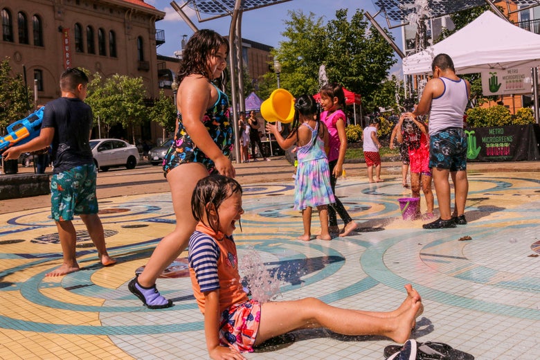 Children play with toys and splash around in a fountain in the Columbia Heights neighborhood of D.C.