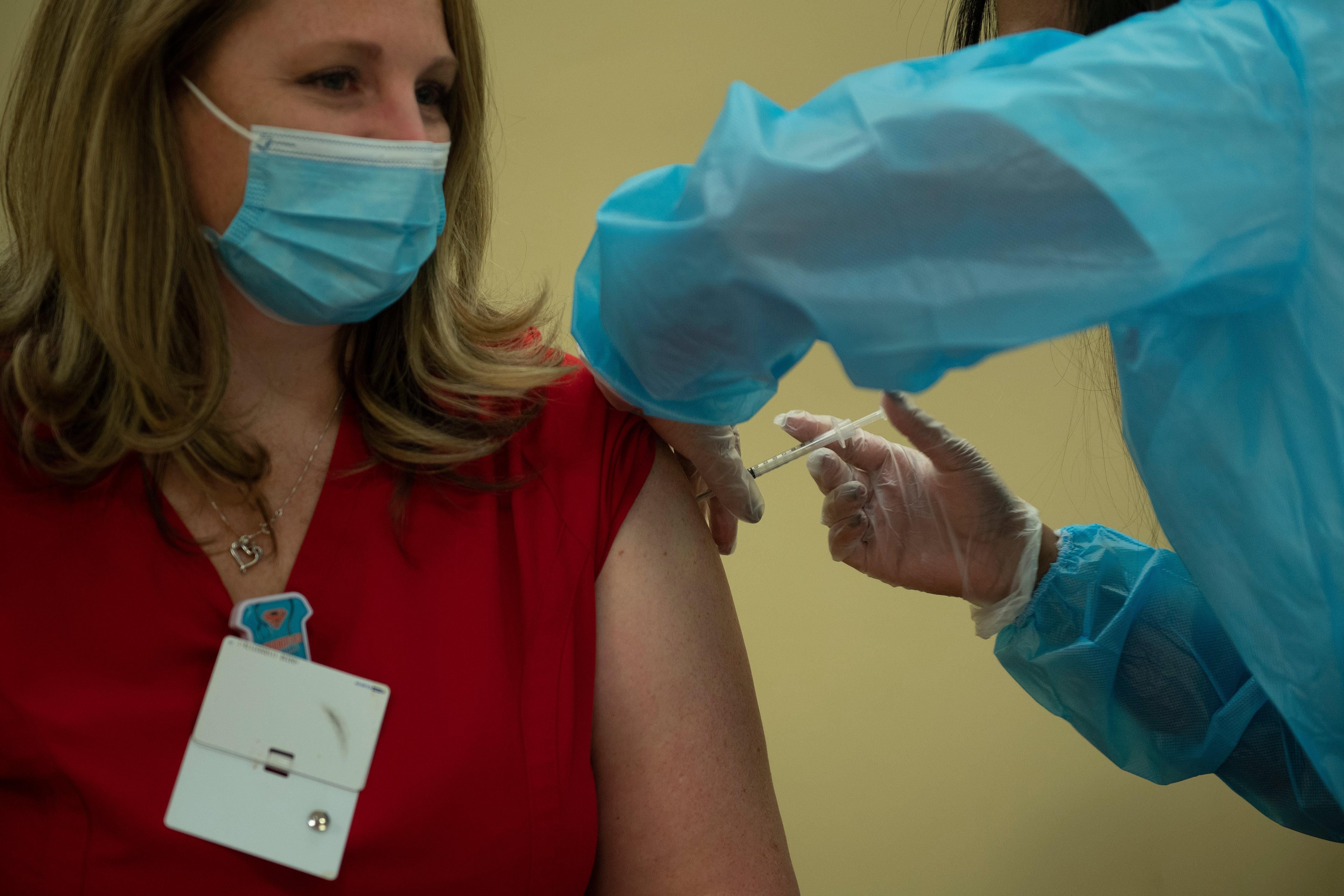 Woman sits to receive COVID vaccine through an injection in her shoulder.