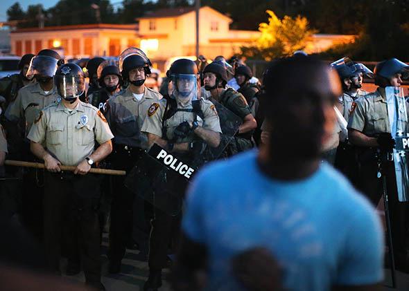 Police stand watch as demonstrators protest the shooting death of teenager Michael Brown.