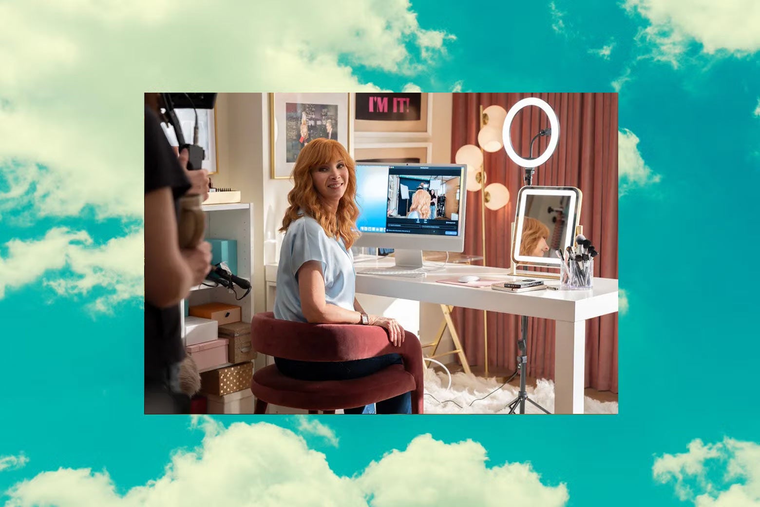 A still from The Comeback depicting Lisa Kudrow at a table with livestreaming equipment.