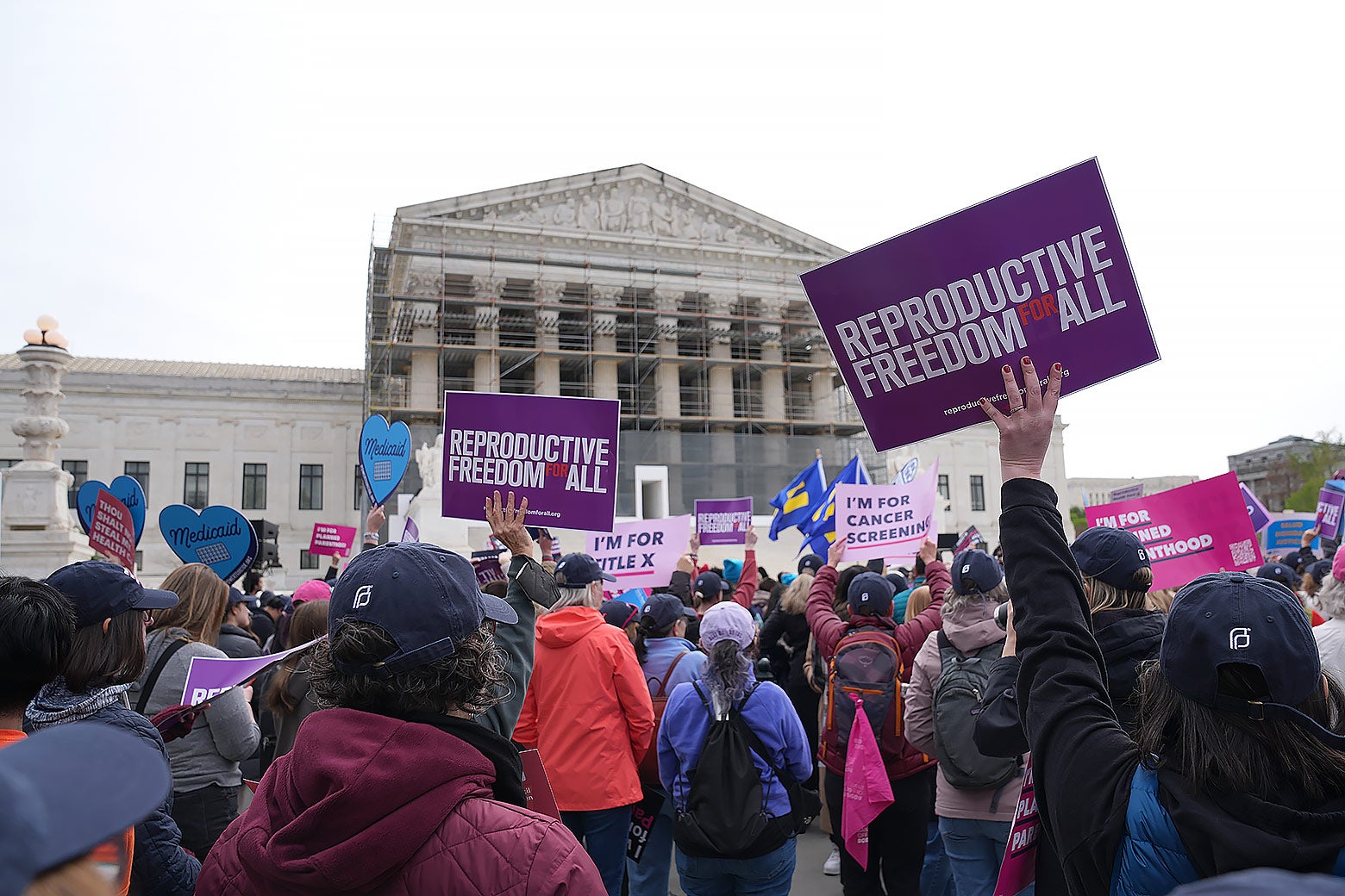 Protesters hold signs in front of the Supreme Court reading "reproductive freedom for all."