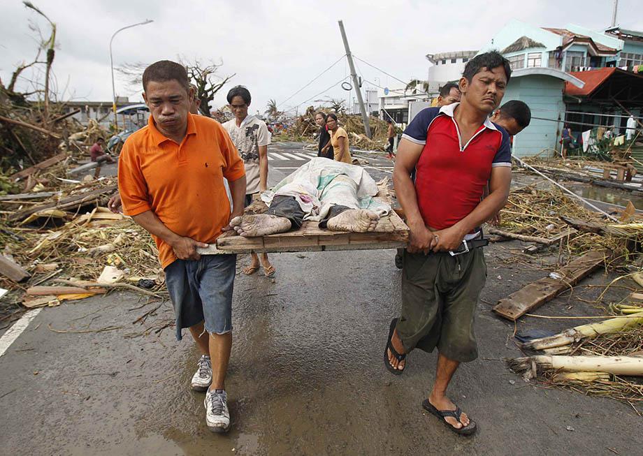 Survivors carry a person killed as super Typhoon Haiyan battered Tacloban city, central Philippines.