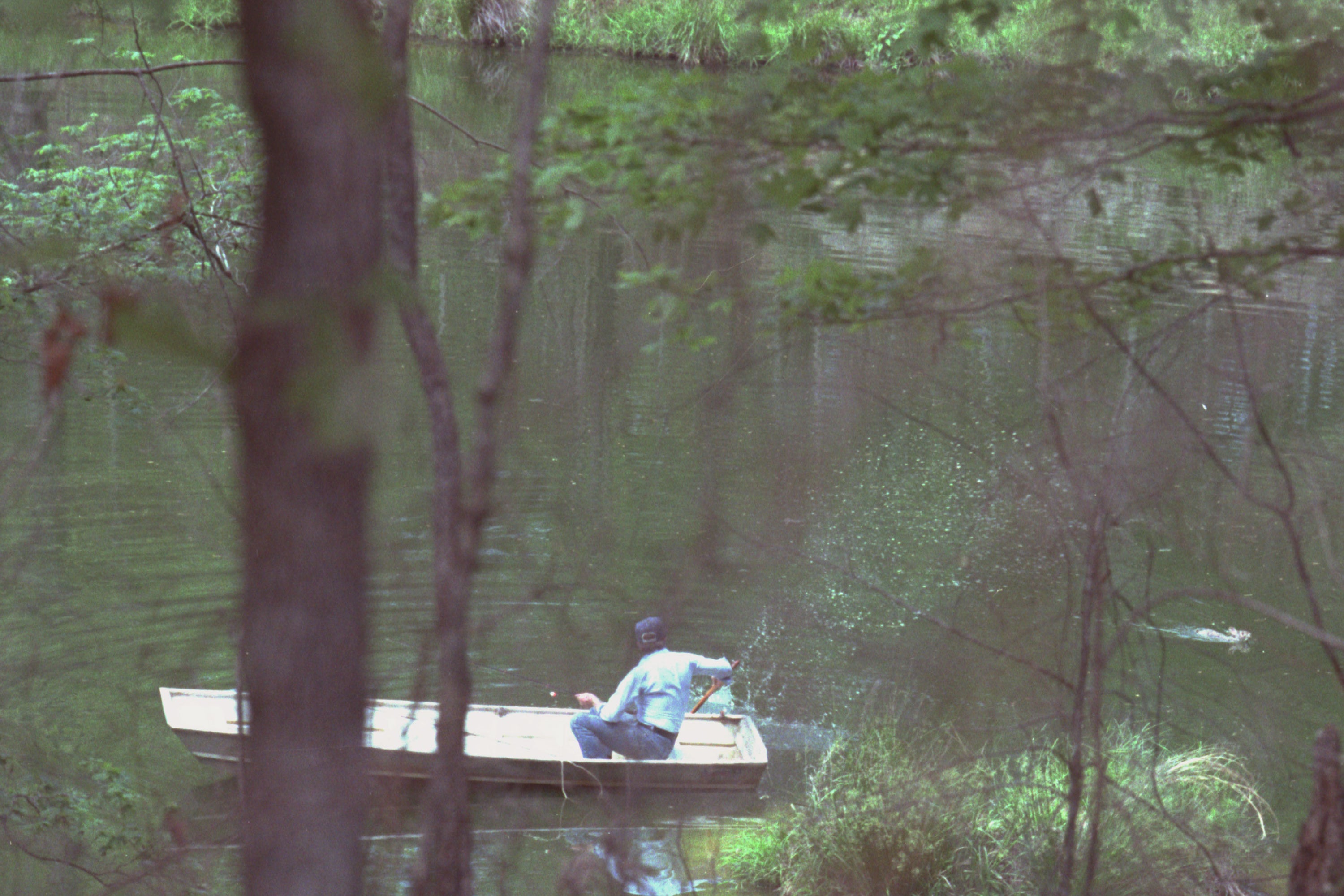 Jimmy Carter in a small boat on a pond, chasing away a swamp rabbit.