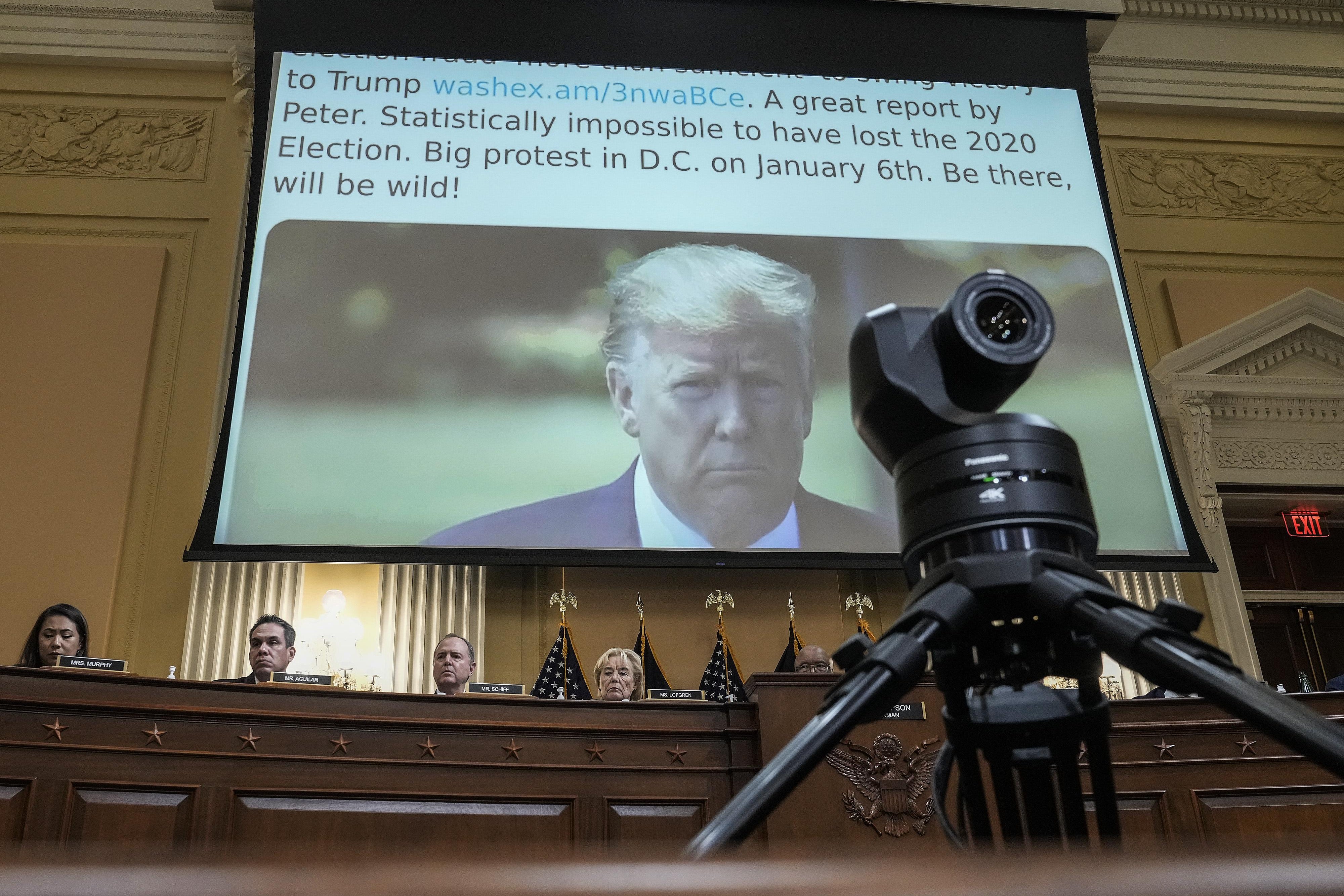Above people sitting at a large desk is a screen that shows a tweet from Donald Trump. It reads in part: "Big protest in D.C. on January 6th. Be there, will be wild!"