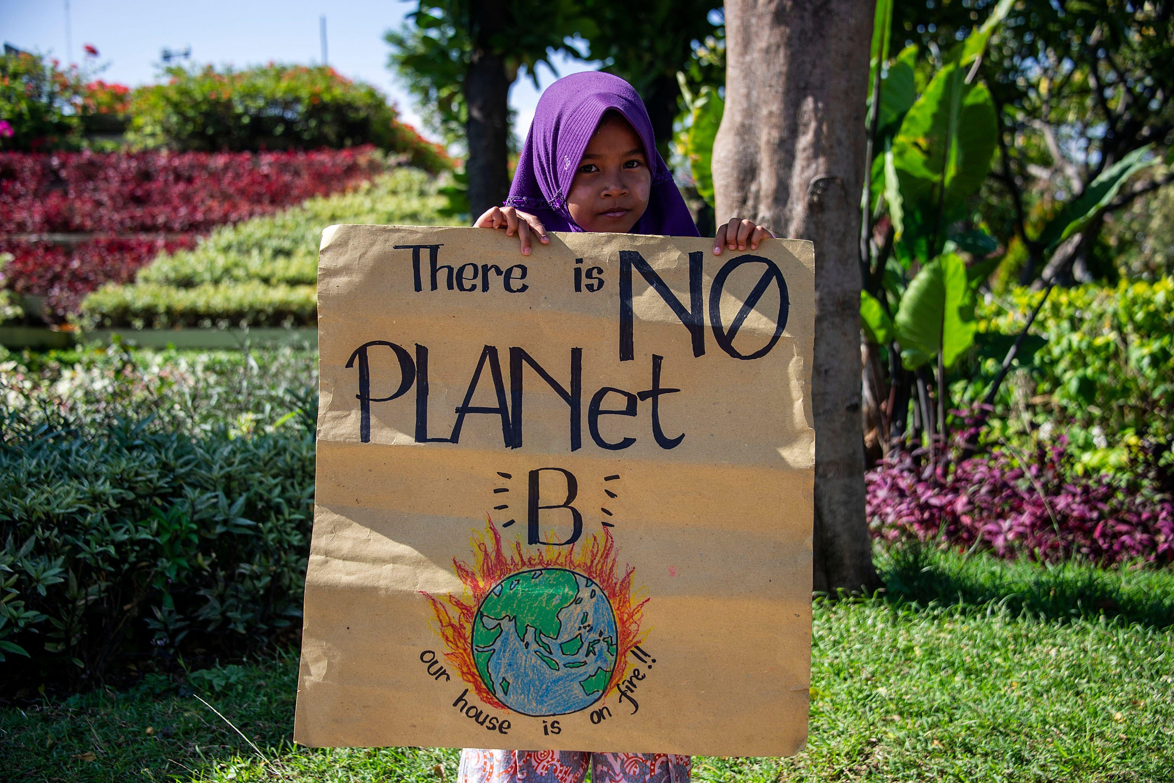 An Indonesian child holds a placard that says "there is no planet b."