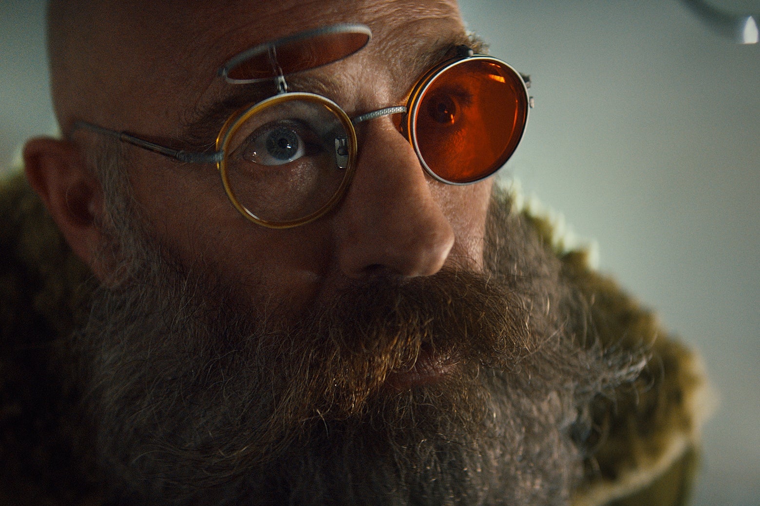 Actor Neil Sandiman, wearing red sunglasses, an immense beard and mustache, and a full-length coat with fur trim.