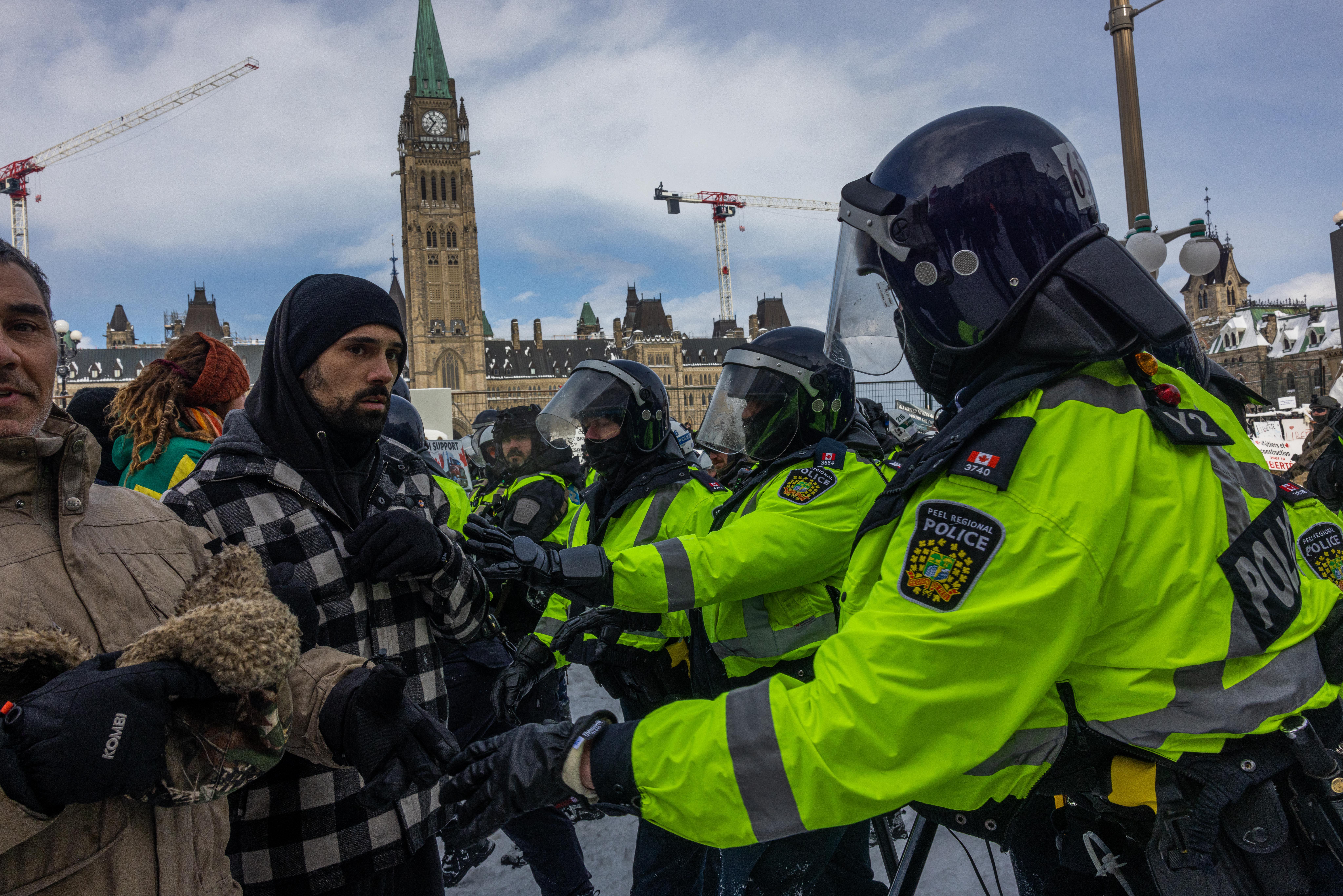 Police face off with demonstrators participating in a protest organized by truck drivers opposing vaccine mandates on Wellington St. on February 19, 2022 in Ottawa, Ontario. 