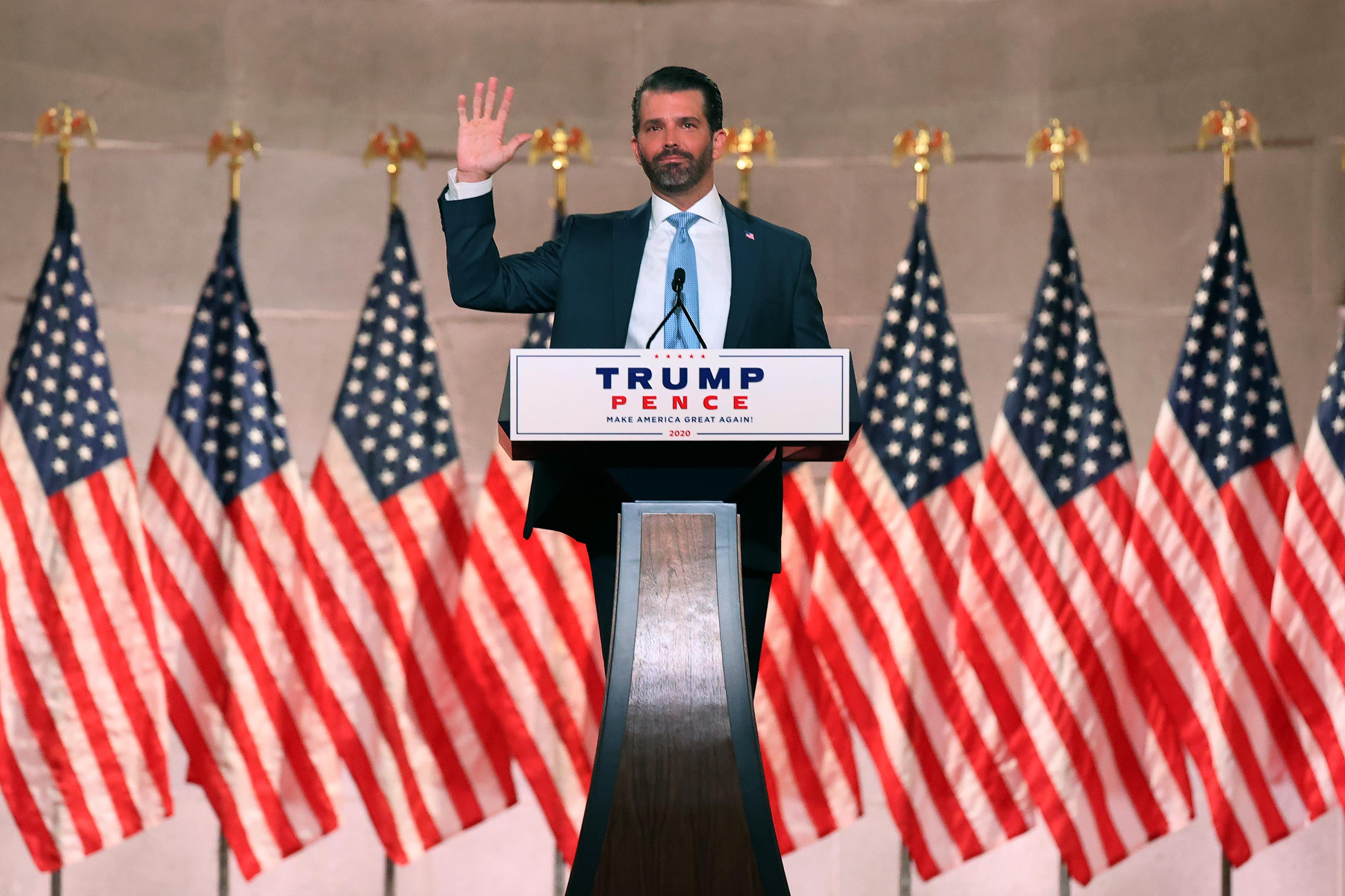 Donald Trump Jr. speaks in front of several American flags. 