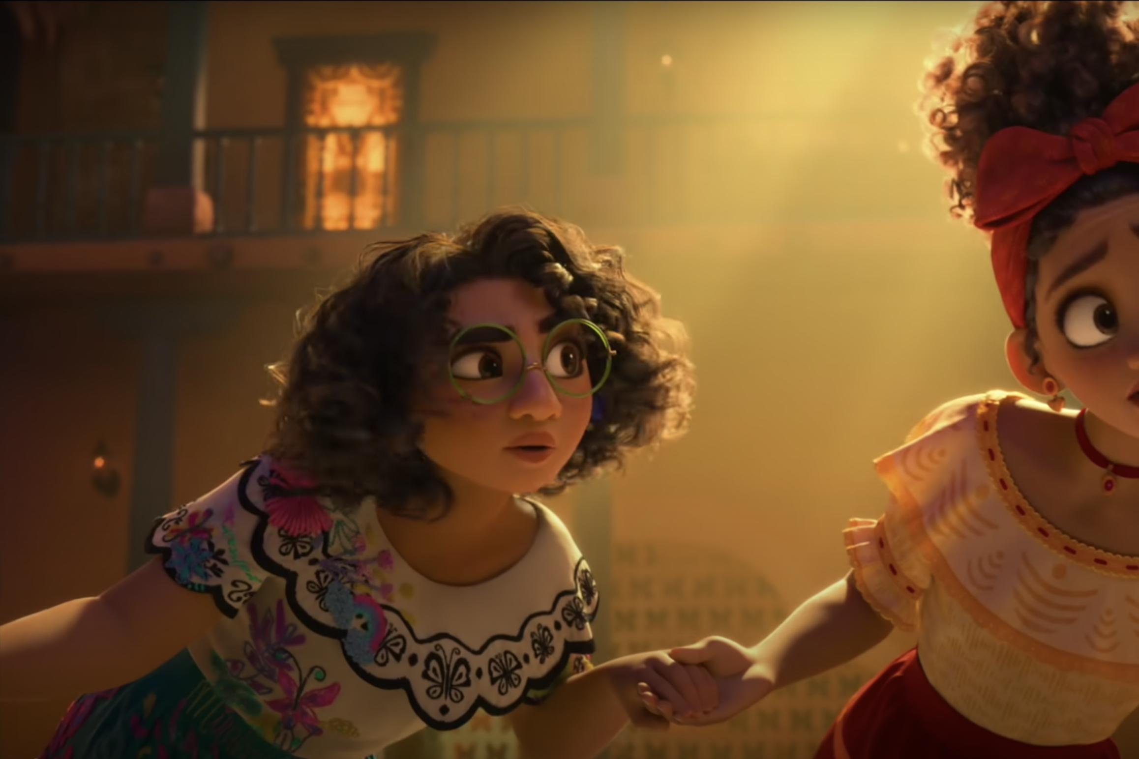 CG still from Encanto of two women in a courtyard holding hands and leaning to the left as if to listen