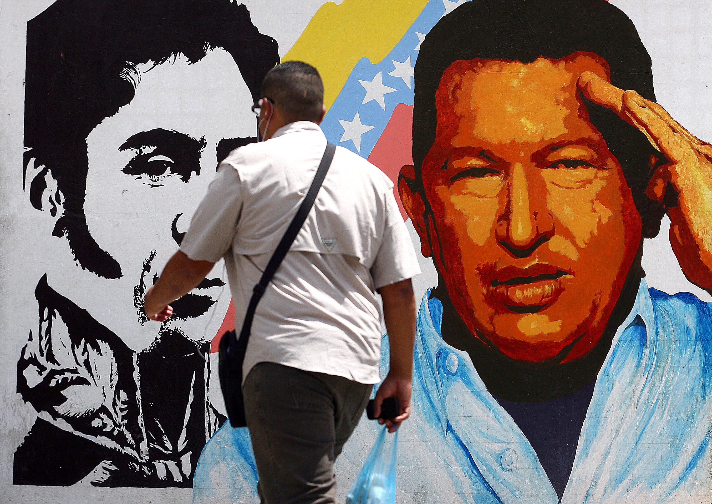 A man walks past a mural portraying the Venezuelan flag, President Hugo Chávez, and South American liberator Simon Bolivar at the 23 de Enero neighborhood, in Caracas, Venezuela, on March 5, 2013.