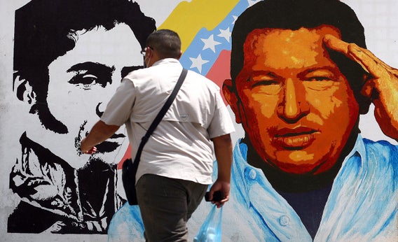 A man walks past a mural portraying the Venezuelan flag, President Hugo Chávez, and South American liberator Simon Bolivar at the 23 de Enero neighborhood, in Caracas, Venezuela, on March 5, 2013.