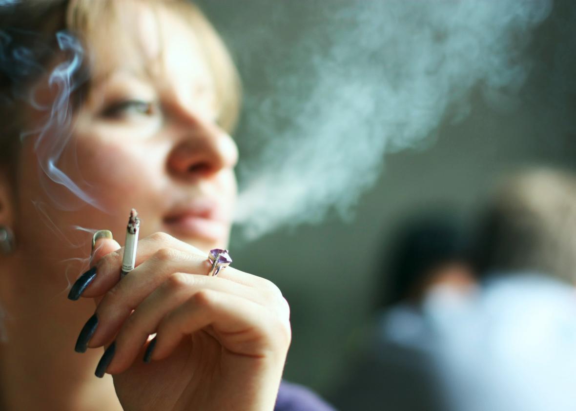 A young woman smoking cigarette inside.