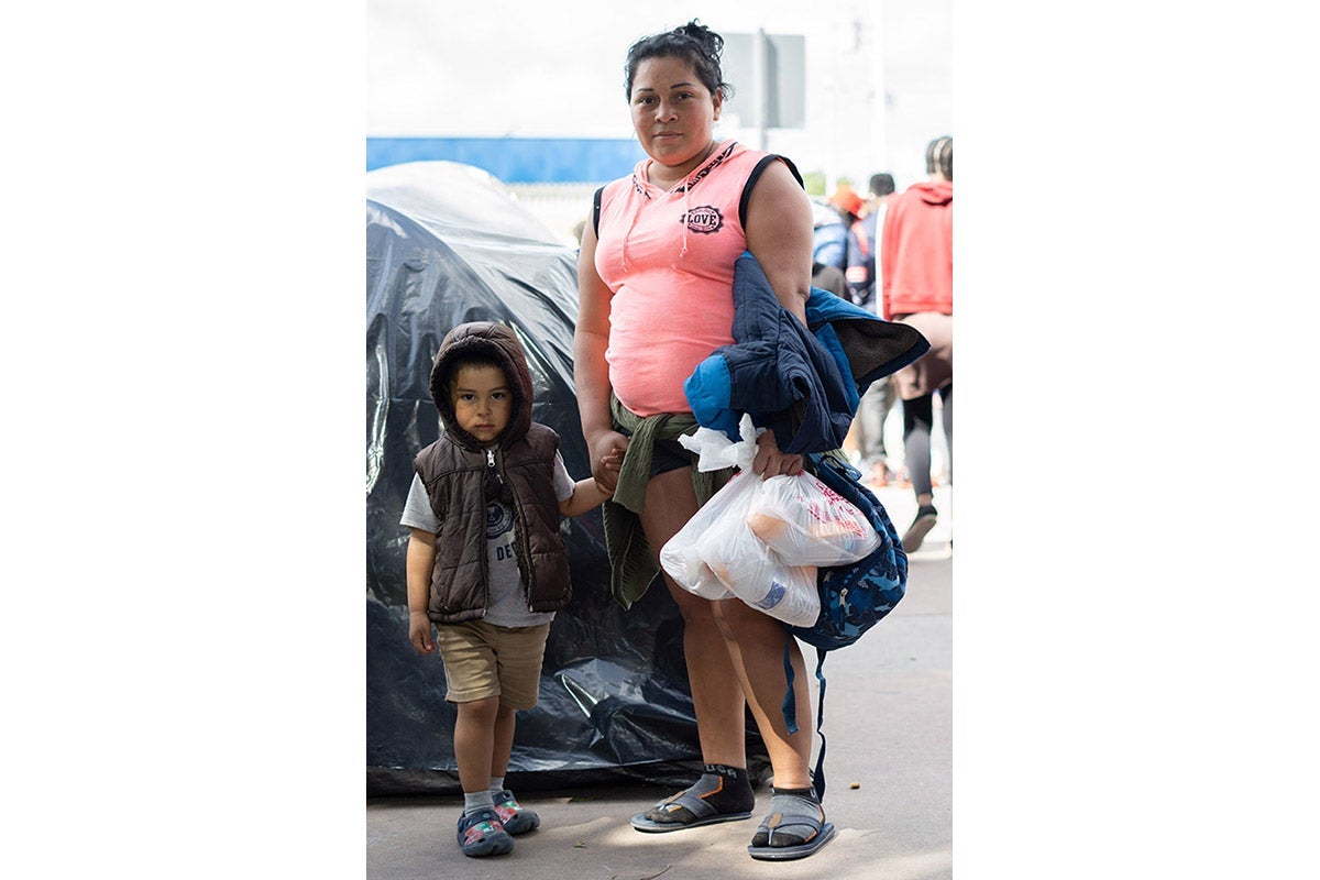 A woman holds a small boy's hand.