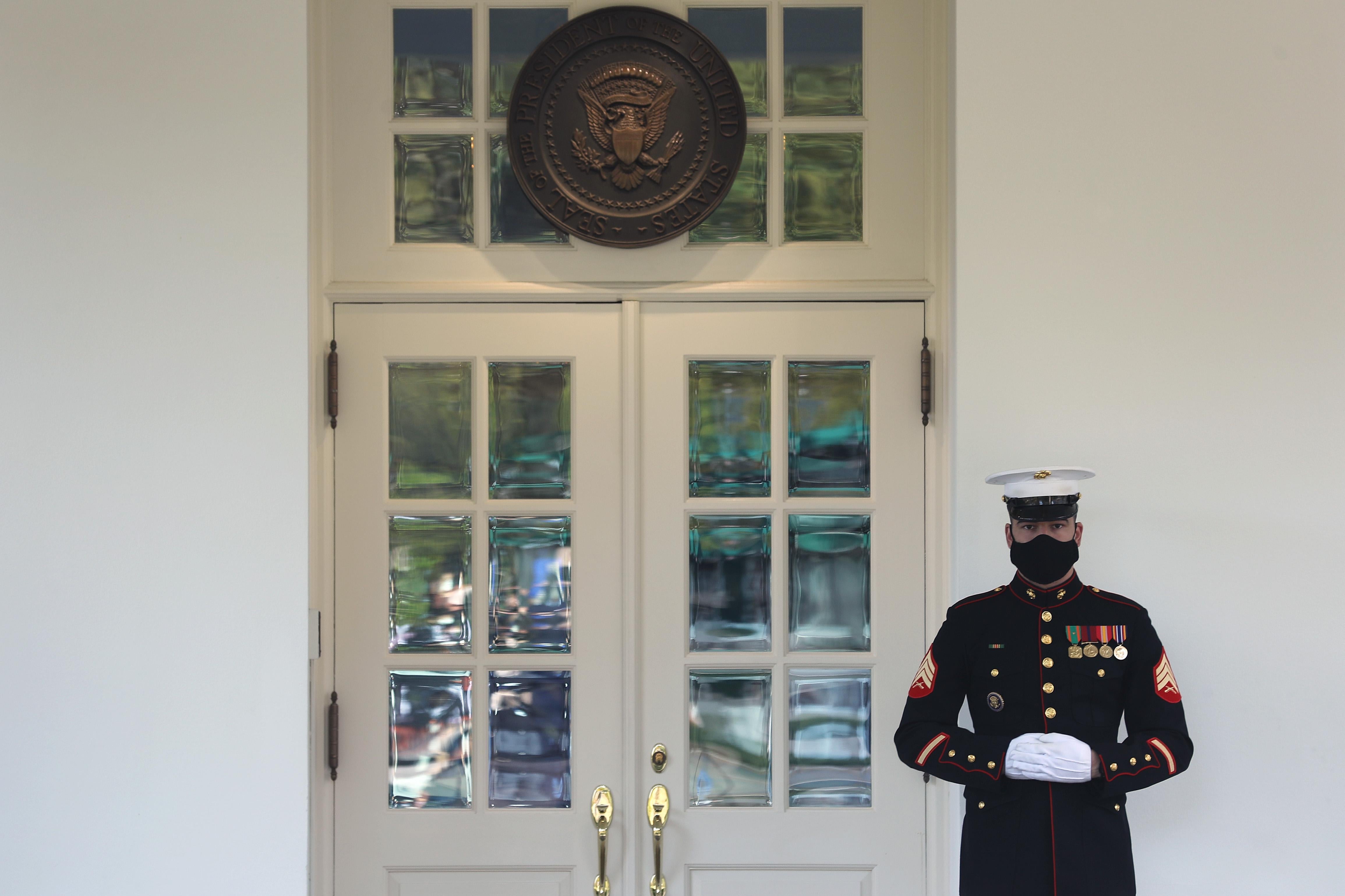 A masked U.S. Marine stands guard outside the West Wing of the White House on Friday