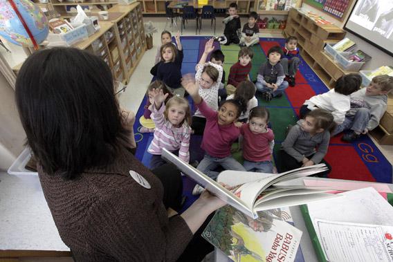 Students in Connie Levin's kindergarten class raise their hands to answer questions during story time.