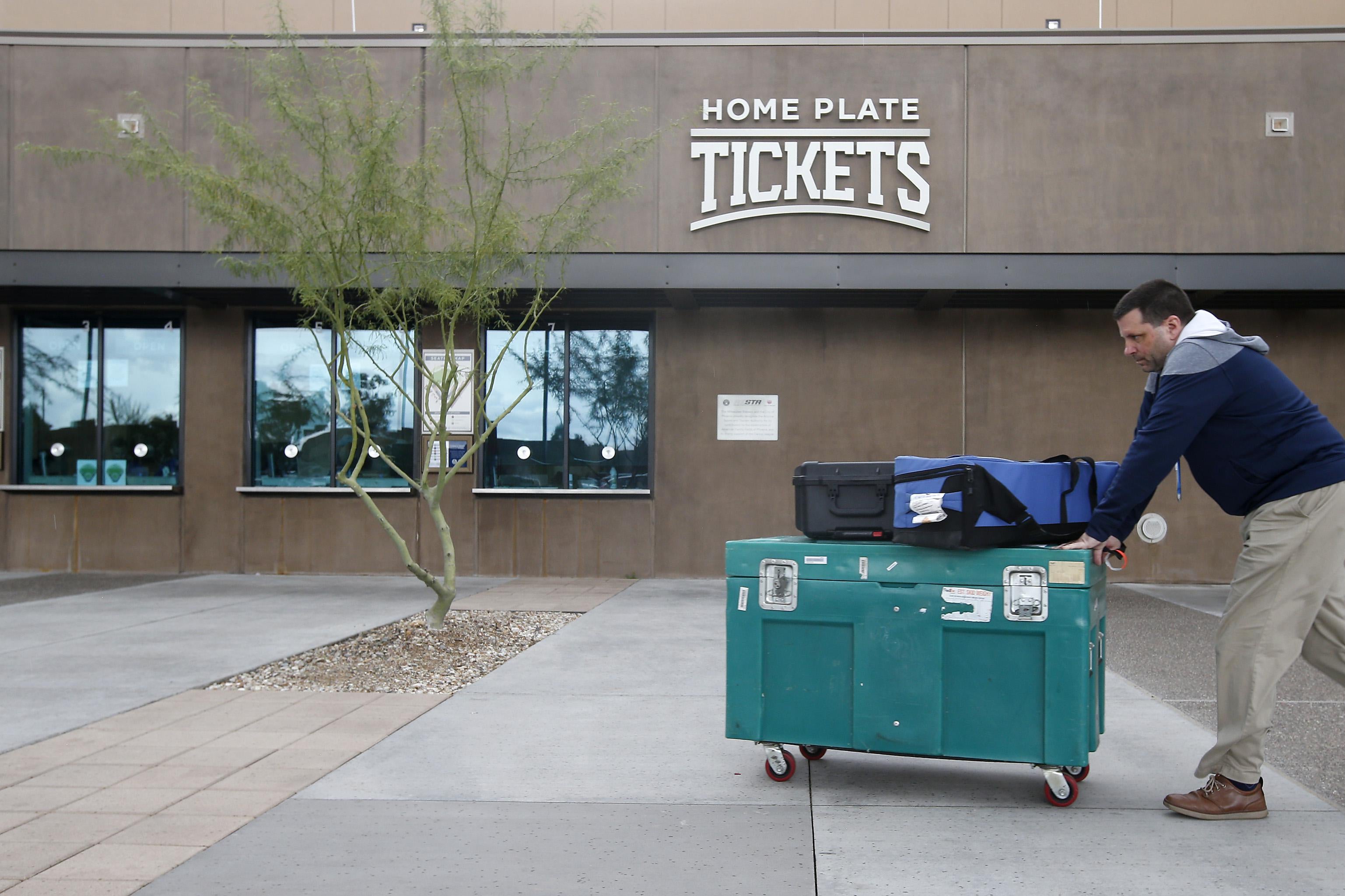 Stadium personnel move equipment past the ticket windows at American Family Fields stadium, spring training home of the Milwaukee Brewers, following Major League Baseball’s decision to suspend all spring training games on March 12, 2020 in Phoenix, Arizona.