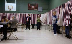 Ballot Inspectors hold the curtains open for voters to enter the voting booth as people vote at the Parker Varney School on election day January 8, 2008 in Manchester, New Hampshire. 