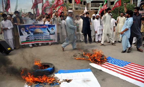 Pakistani Shiite Muslims shout slogans beside a burning Israeli flag during a rally against Israel and the United States.