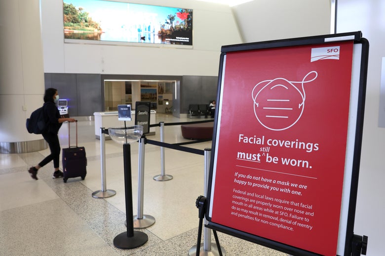 A sign in an airport terminal says facial coverings must be worn.