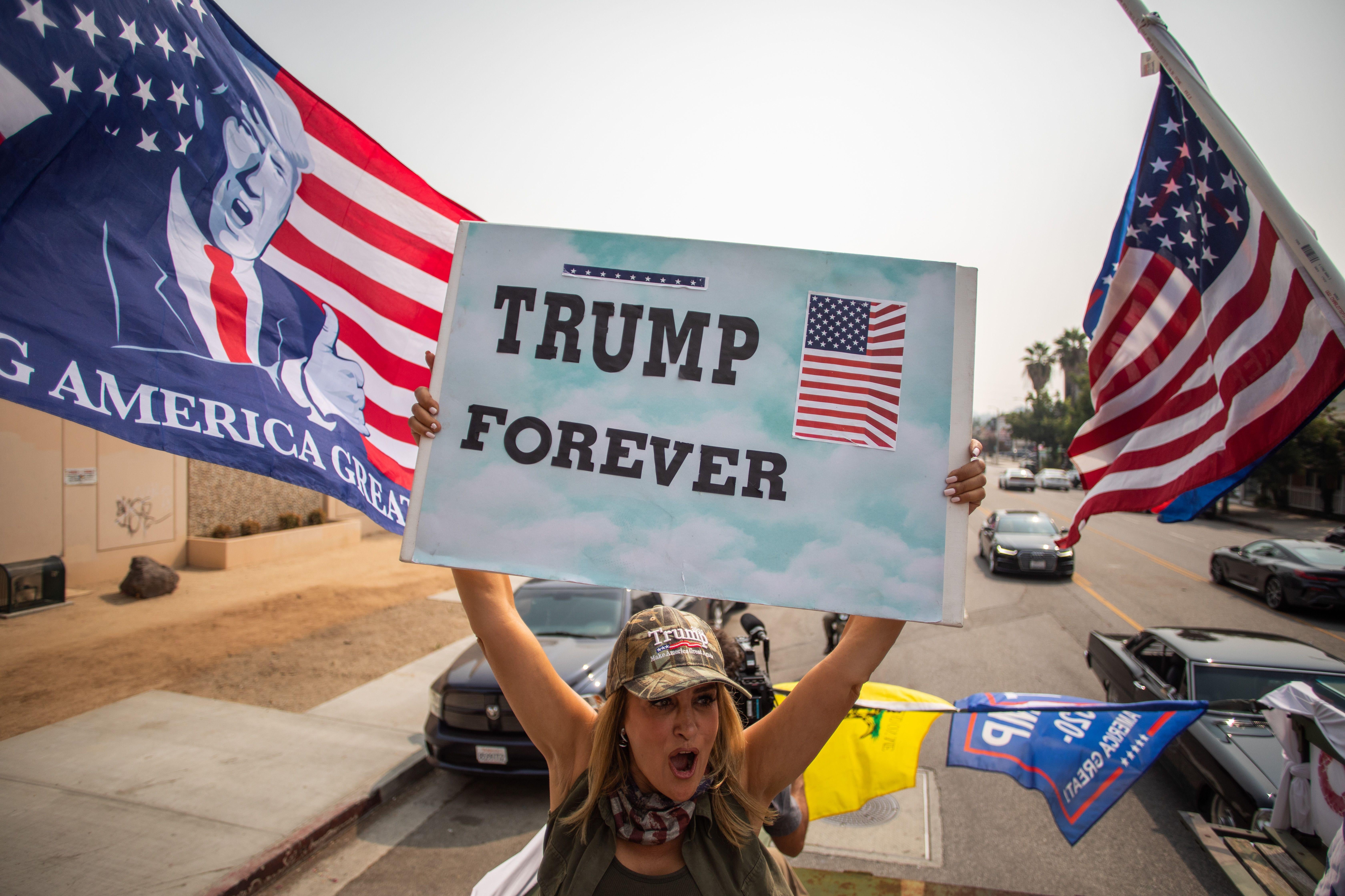 A woman brandishes a "Trump Forever" sign from the back of a military truck.