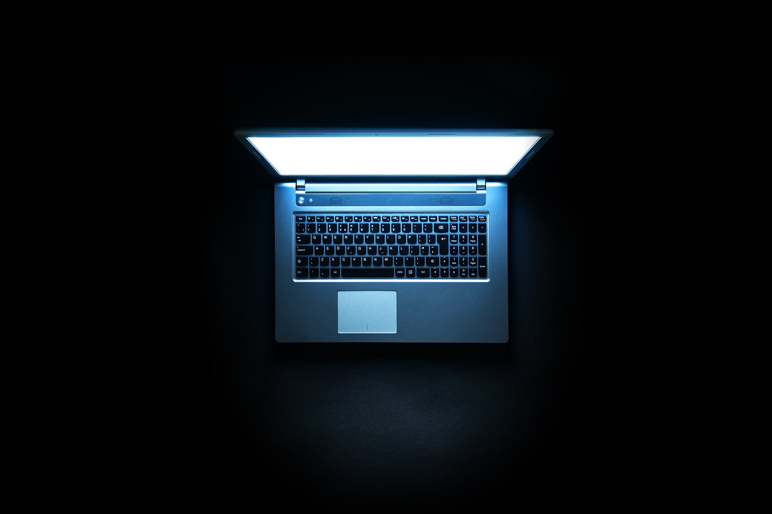 A laptop glowing in a dark room.