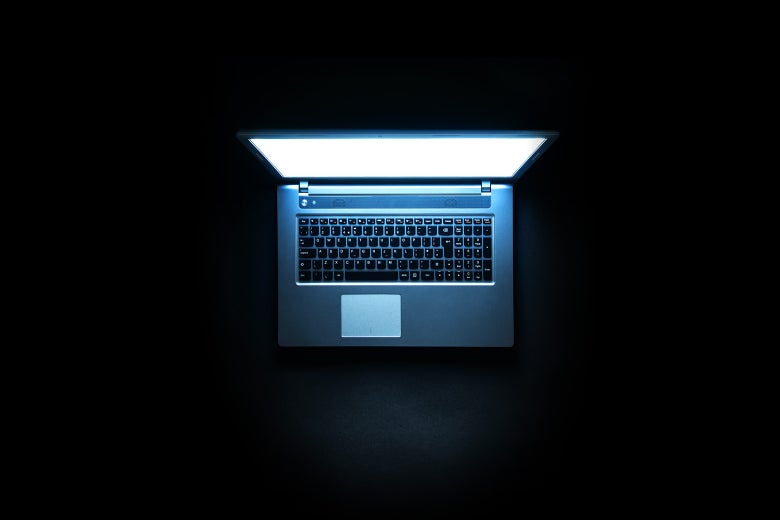 A laptop glowing in a dark room.