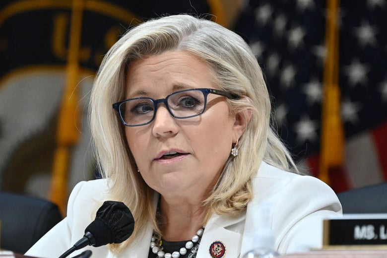 Cheney, seated behind a microphone and wearing a white blazer, looks to her left with a bit of a glint in her eye.