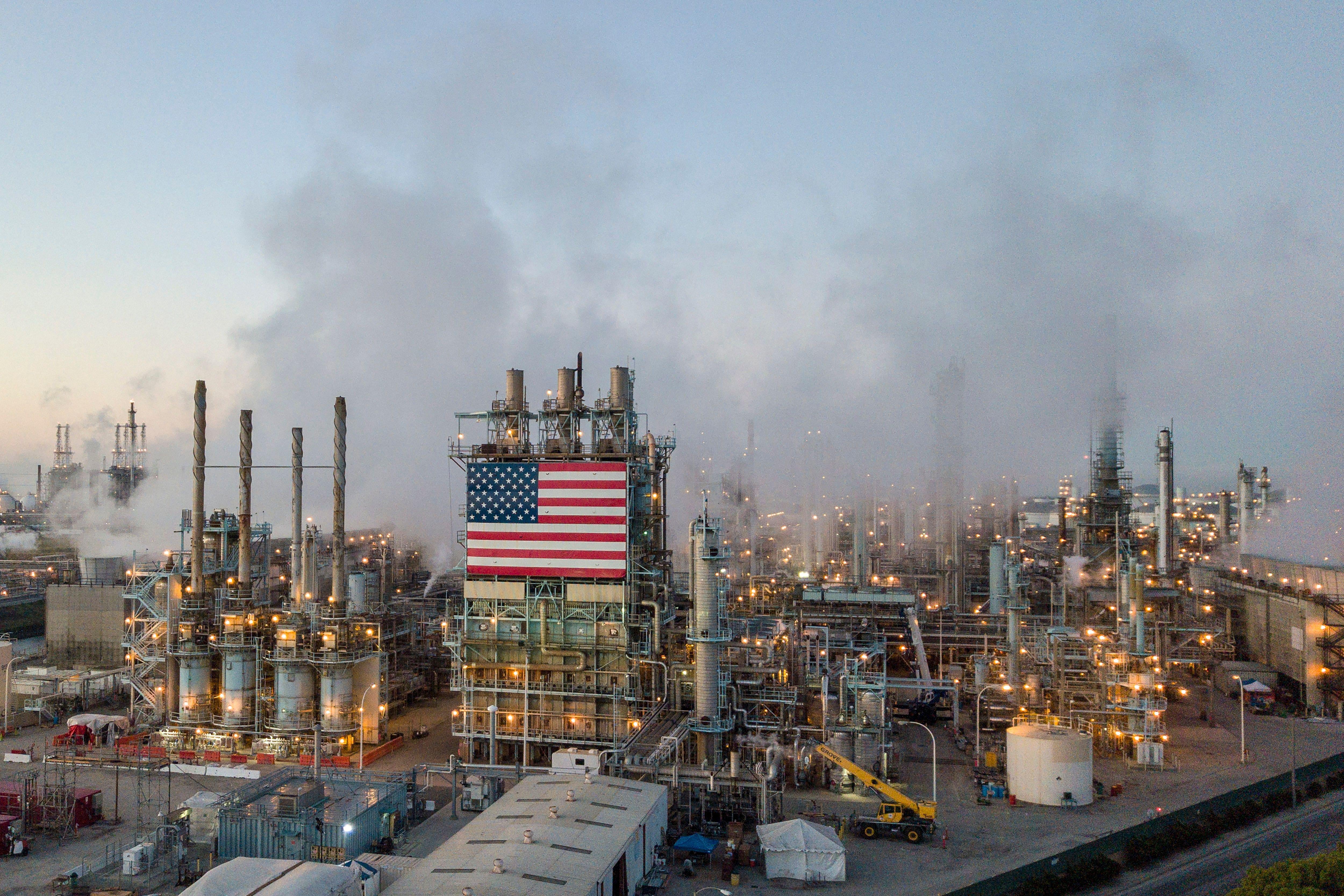 An oil refinery with an American flag is seen spewing smoke.