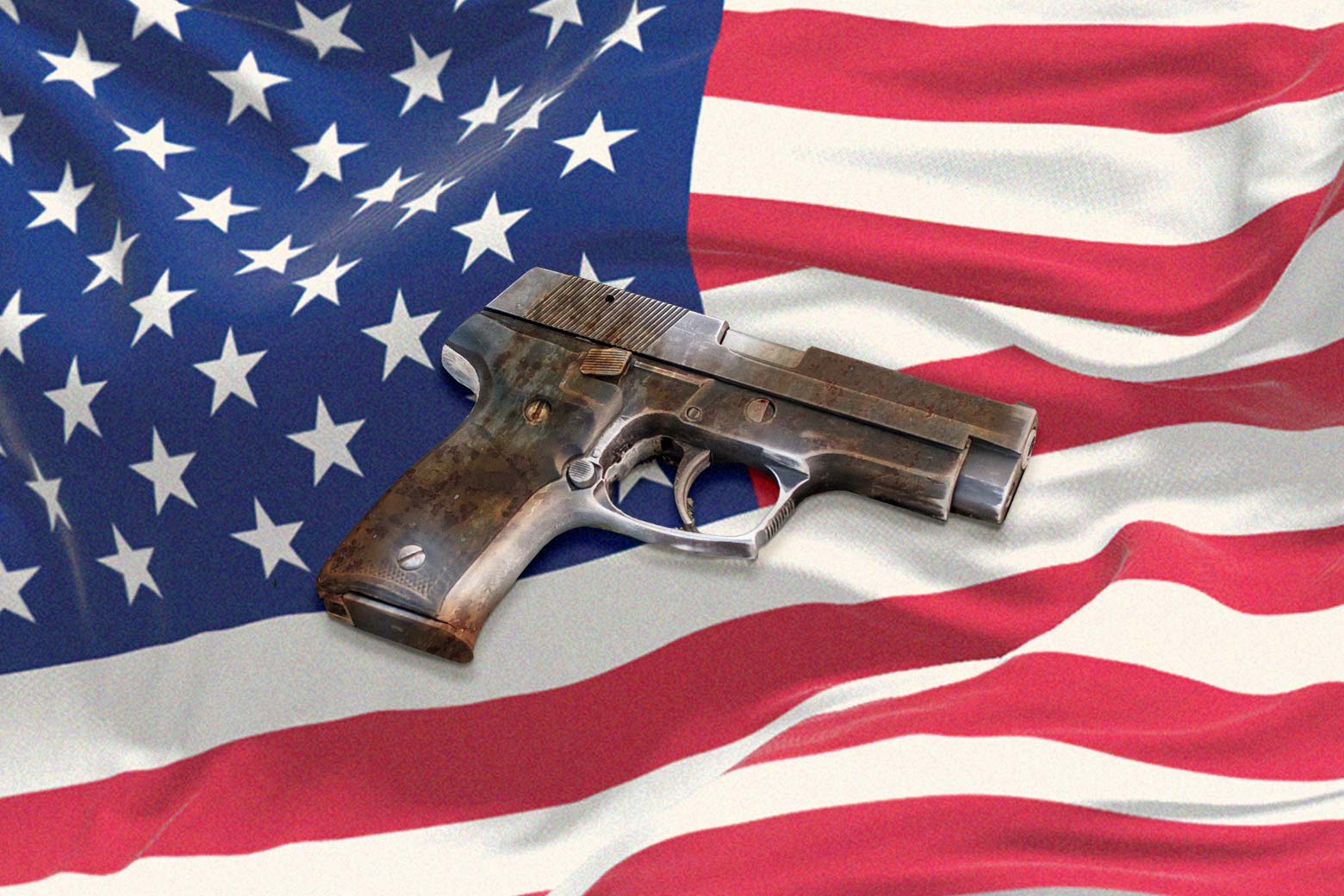 A dirty handgun rests on the American flag.
