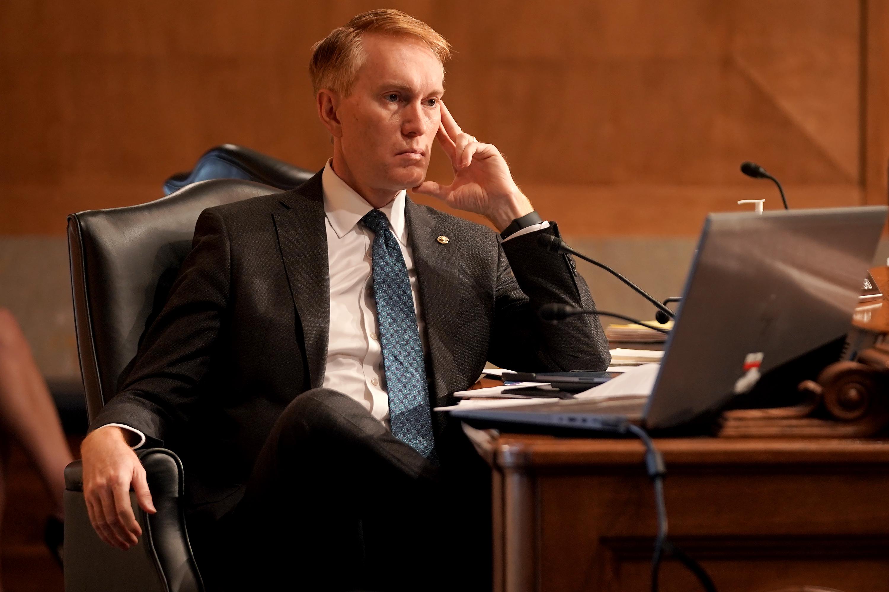 Sen. James Lankford sits with his legs crossed at a table during a committee hearing.