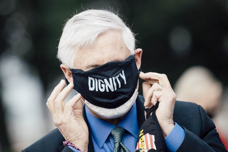 Rep. Fred Upton puts on a face mask that says "Dignity" across the front. The mask covers his eyes, nose, and mouth.