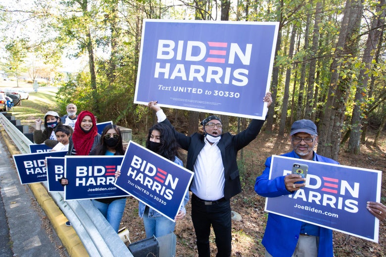 Voters wave Biden-Harris campaign signs at the entrance to a polling station.