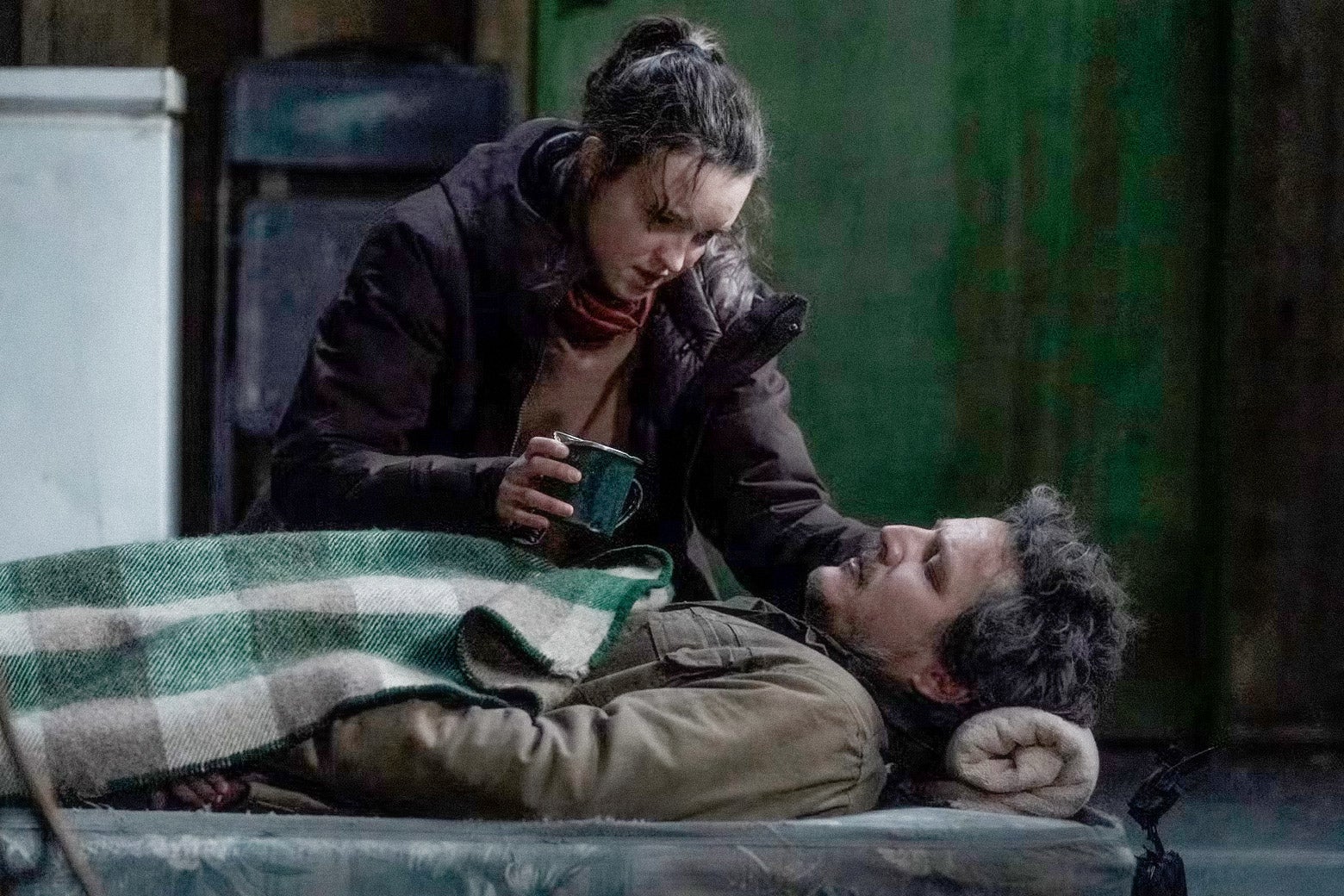 A young woman tends to a man on his sick bed.
