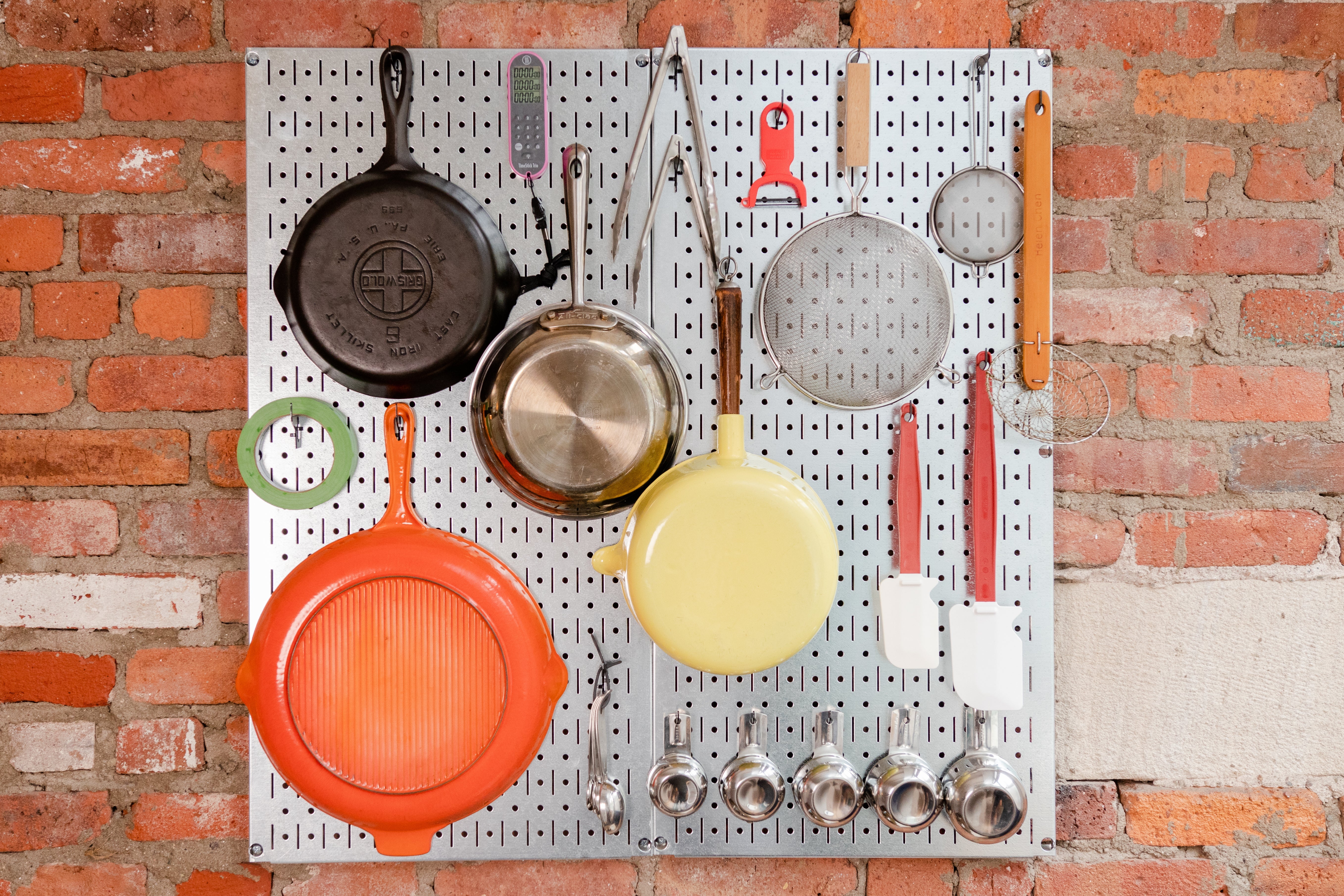 Cookware on a metal pegboard.