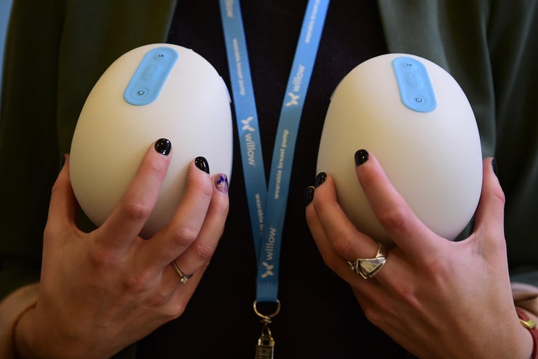 A woman holds in front of her chest the two wireless, dome-shaped breast pumps of the Willow breast pump.