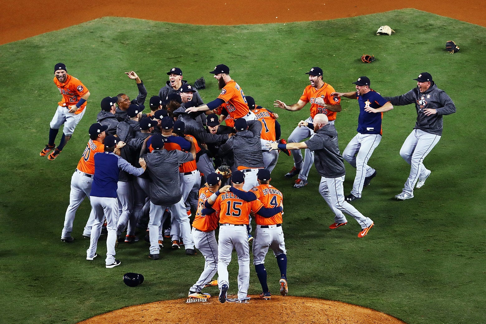Astros team members rush toward one another near the pitcher’s mound.