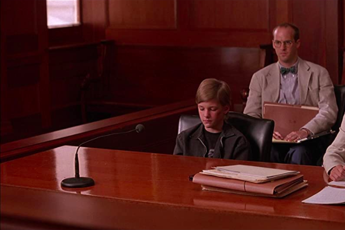 Susan Sarandon and Anthony Edward sit behind a table in a courtroom.